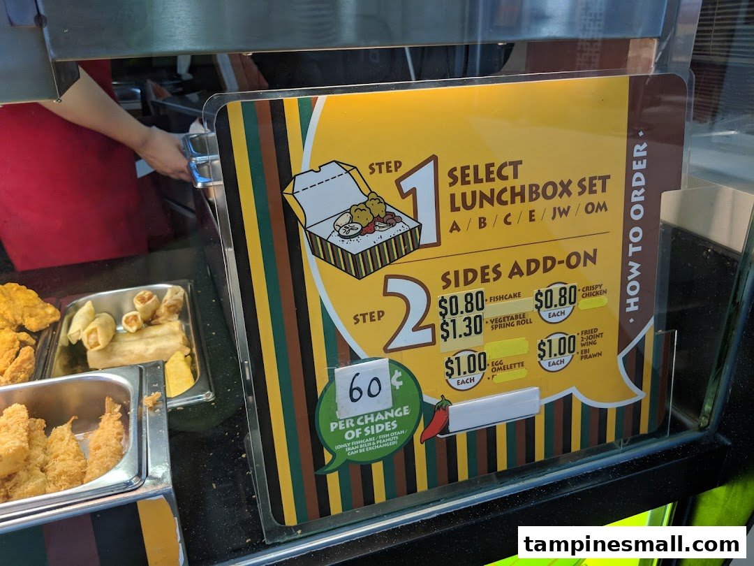 A menu board displaying lunchbox sets and various side add-ons with prices, alongside a food display.