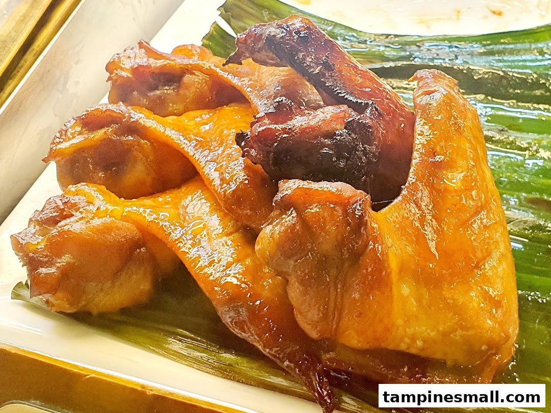 Close-up of succulent roasted chicken pieces served on a banana leaf.