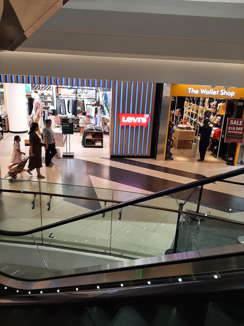 View of Levi's shop entrance and interior from a mall escalator, with shoppers.