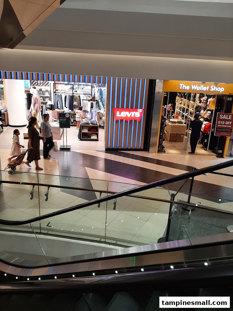 View of Levi's shop entrance and interior from a mall escalator, with shoppers.