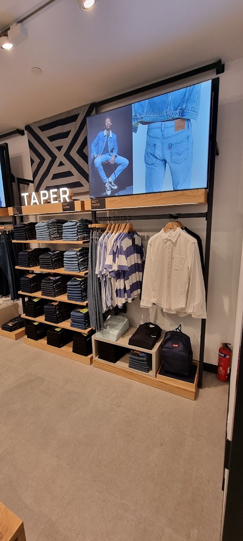 Interior view of Levi's store showcasing folded jeans, hanging apparel, and a digital display.