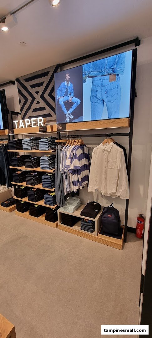 Interior view of Levi's store showcasing folded jeans, hanging apparel, and a digital display.
