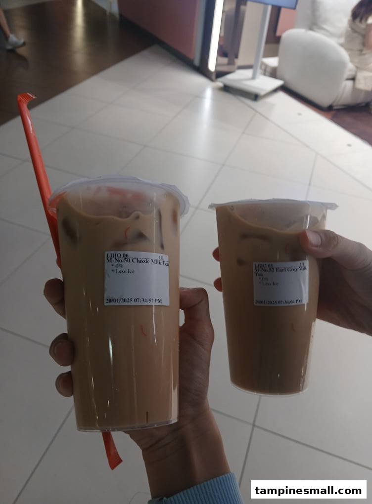 Two hands holding two bubble tea drinks from LiHO TEA, featuring Classic Milk Tea and Earl Grey Milk Tea.