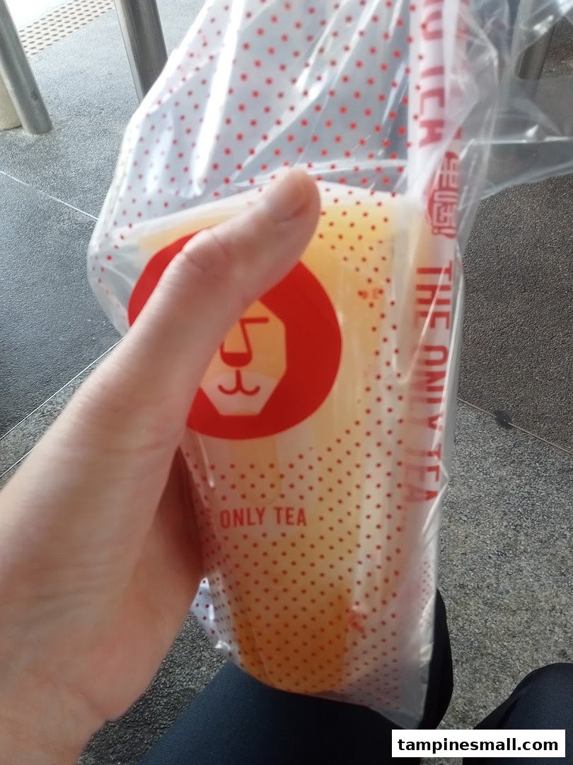 A hand holds a refreshing LiHO TEA drink in a branded cup and carrier bag.
