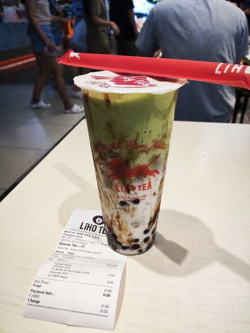 A vibrant LiHO TEA avocado bubble tea with a receipt on a table.