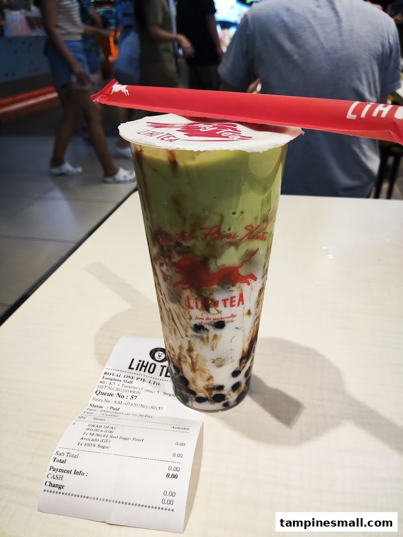 A vibrant LiHO TEA avocado bubble tea with a receipt on a table.