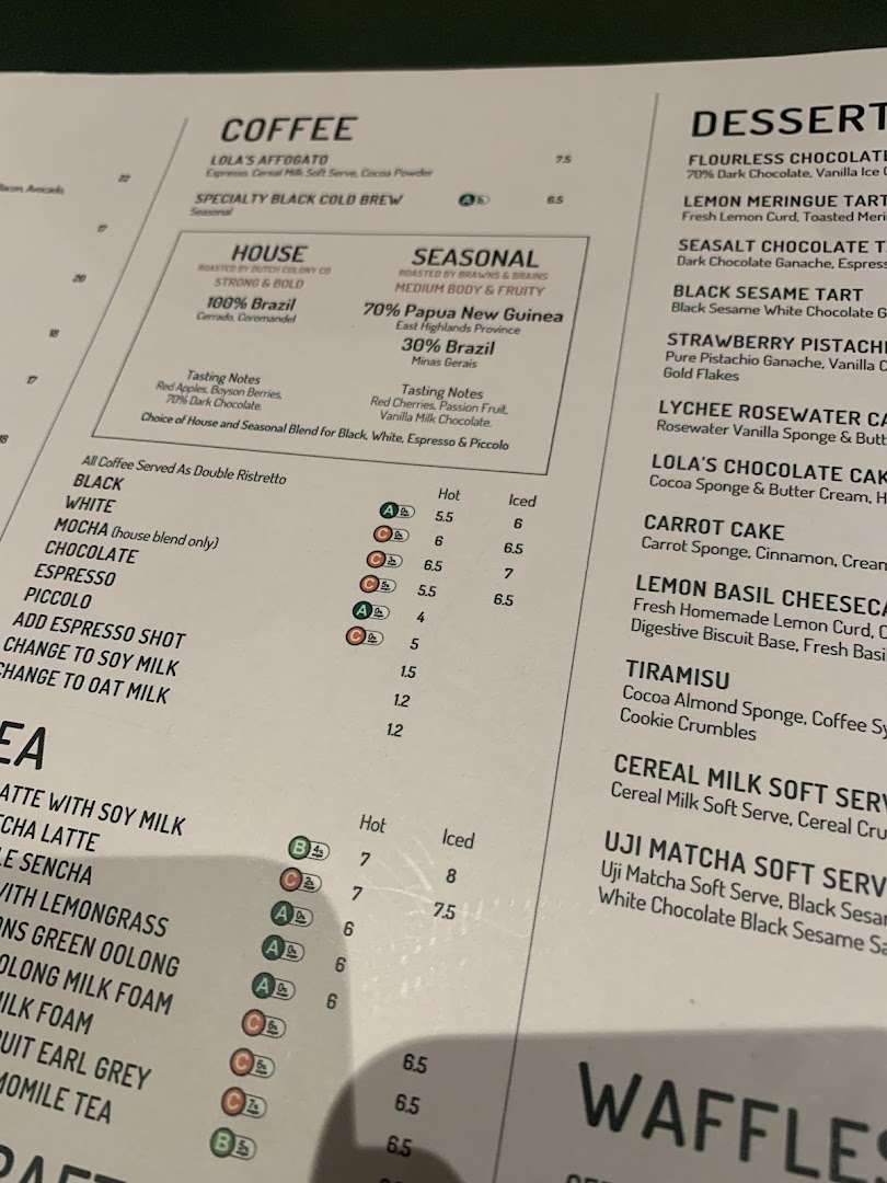A close-up view of Lola's cafe menu, featuring coffee, tea, and dessert selections.