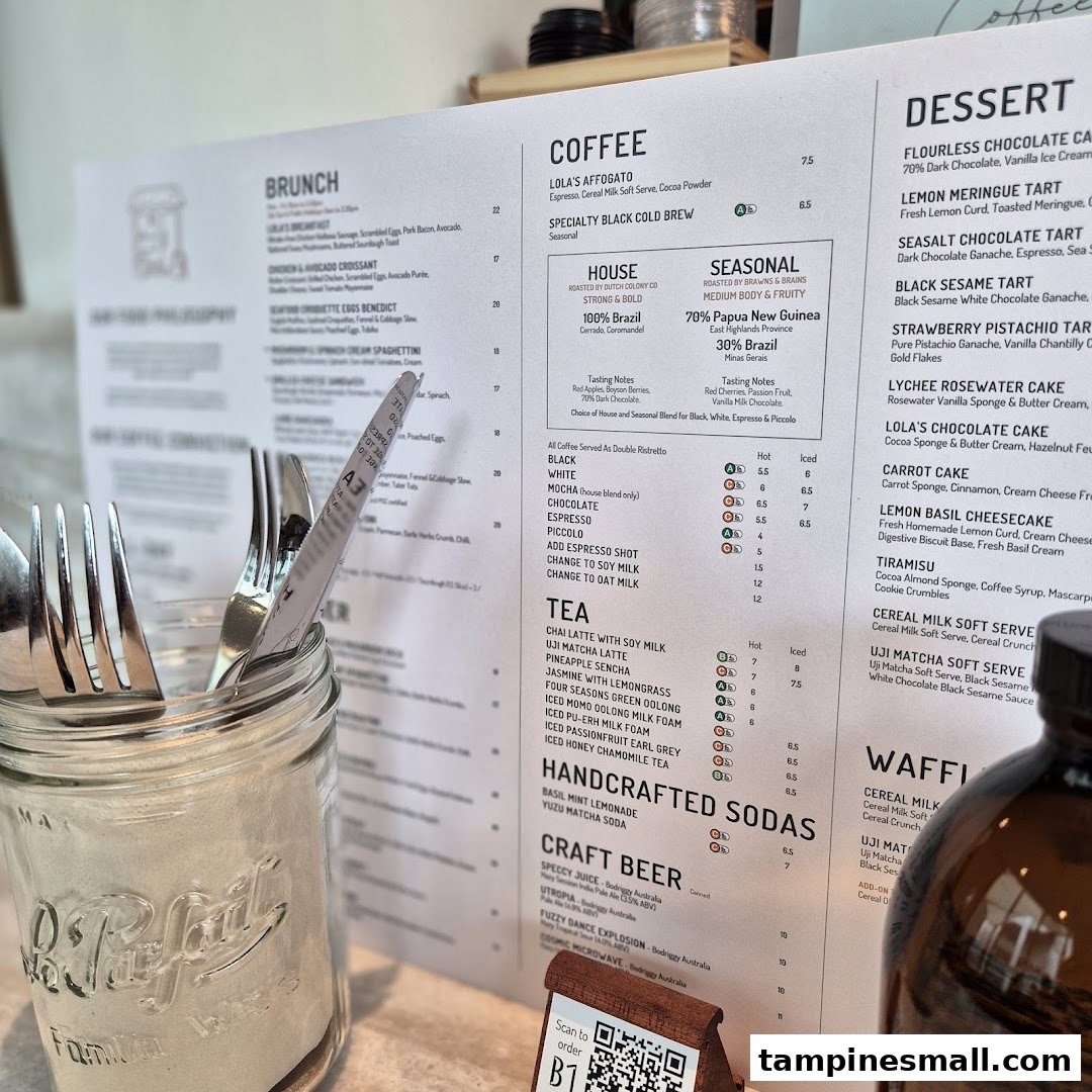 A close-up of Lola's cafe menu, featuring brunch, coffee, tea, and dessert options, with cutlery in a jar.
