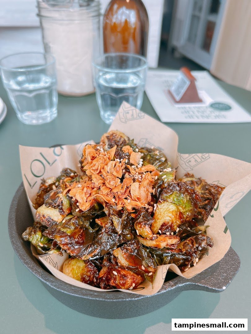 A close-up of roasted Brussels sprouts with crispy toppings served in a bowl at Lolas.