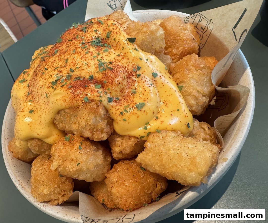 A close-up of crispy tater tots generously topped with melted cheese sauce, paprika, and herbs in a bowl.