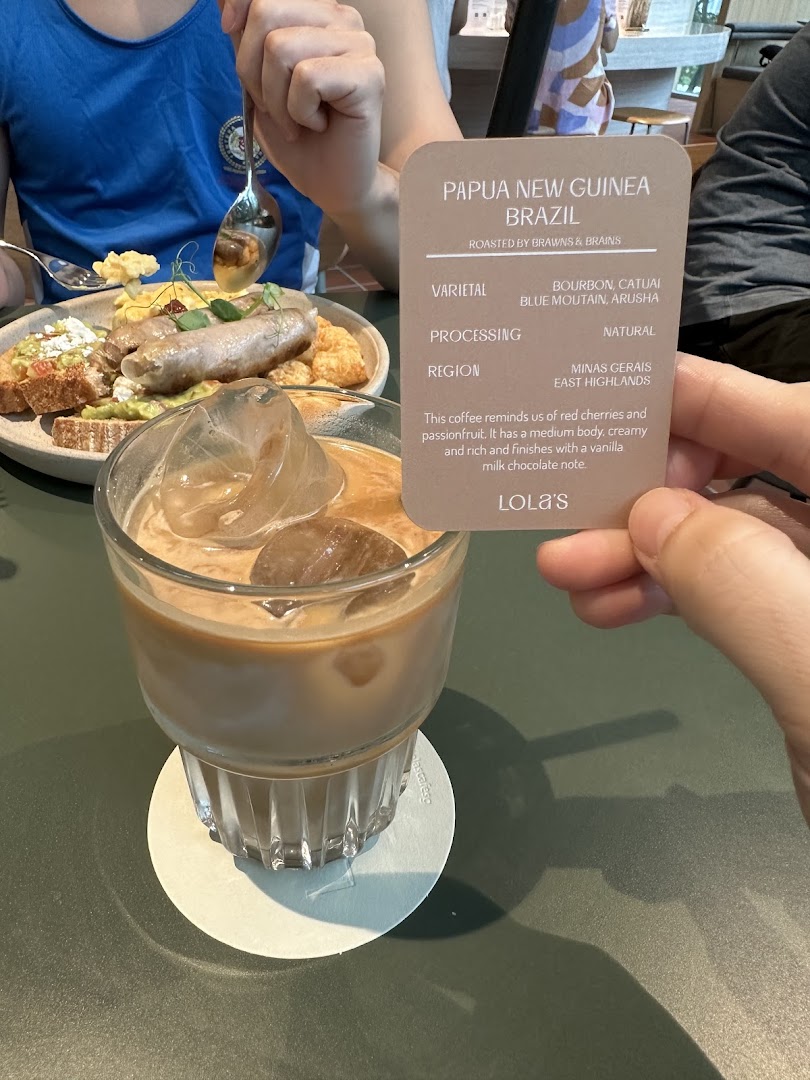 An iced coffee and a food plate on a table, with a descriptive card for the coffee blend.
