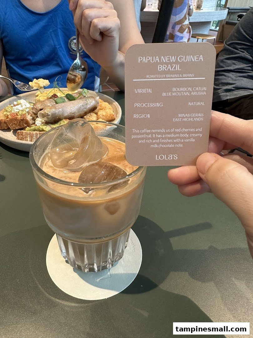 An iced coffee and a food plate on a table, with a descriptive card for the coffee blend.