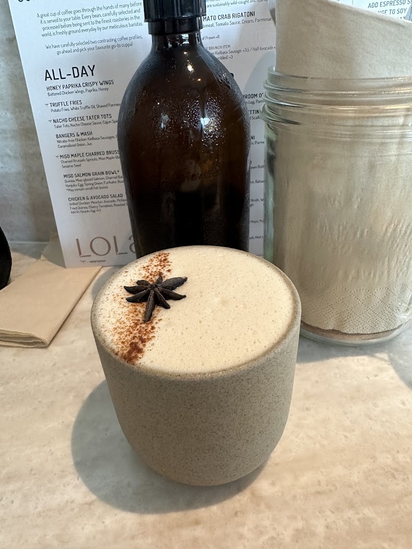 A beautifully garnished drink on a table with a menu and beverage bottle.