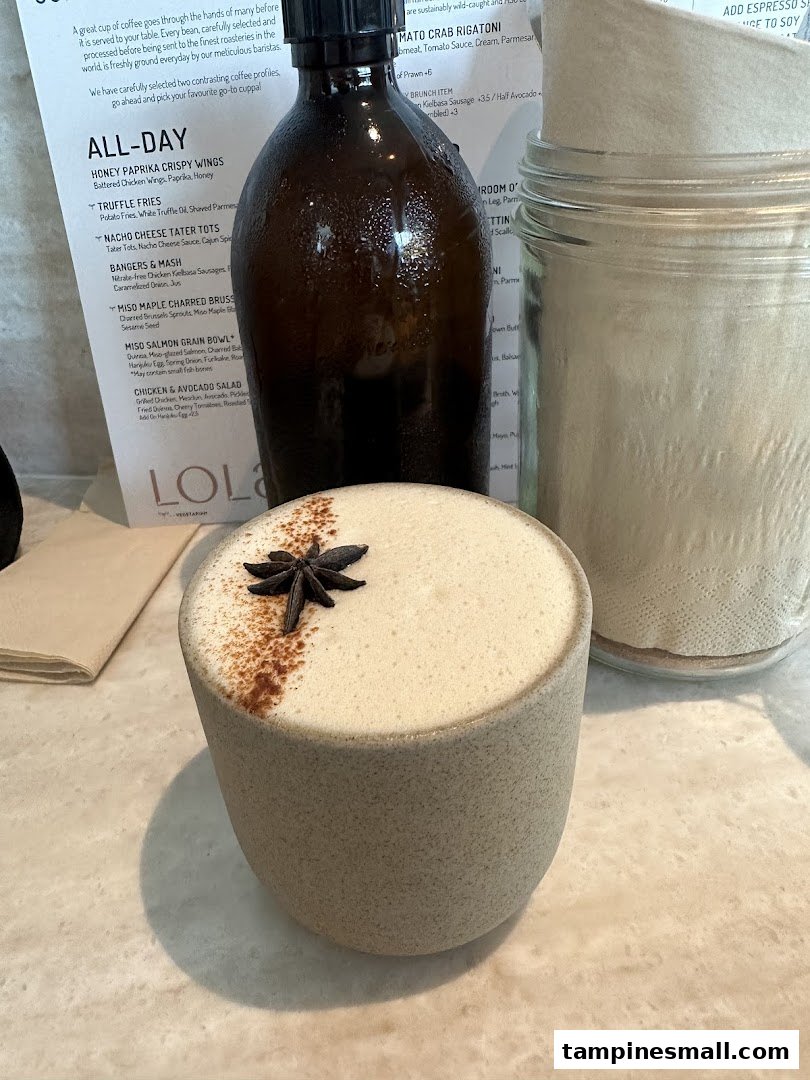 A beautifully garnished drink on a table with a menu and beverage bottle.