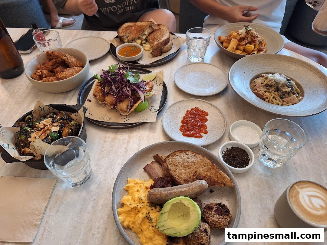 A table laden with diverse, delicious dishes and drinks, including pasta, wings, and a full breakfast spread.