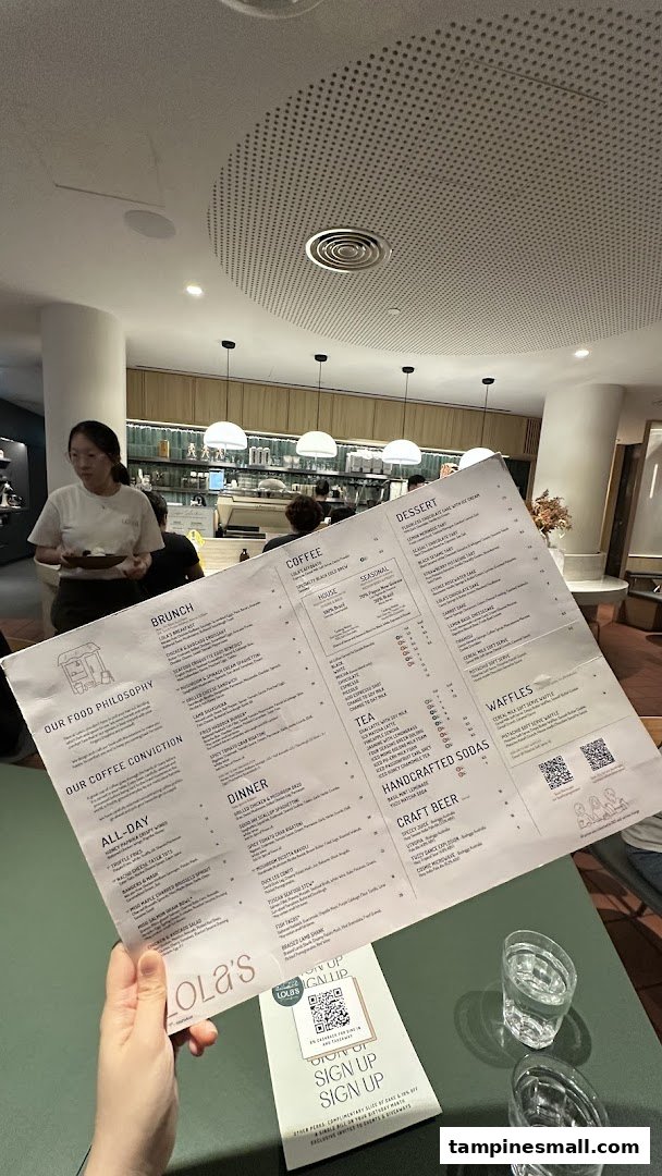 A person holding a detailed menu for Lola's cafe, showcasing various food and drink options.