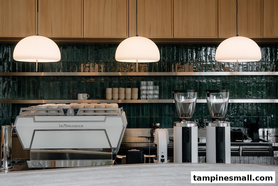 A modern coffee bar counter featuring a high-end espresso machine and grinders, set against a stylish tiled wall.