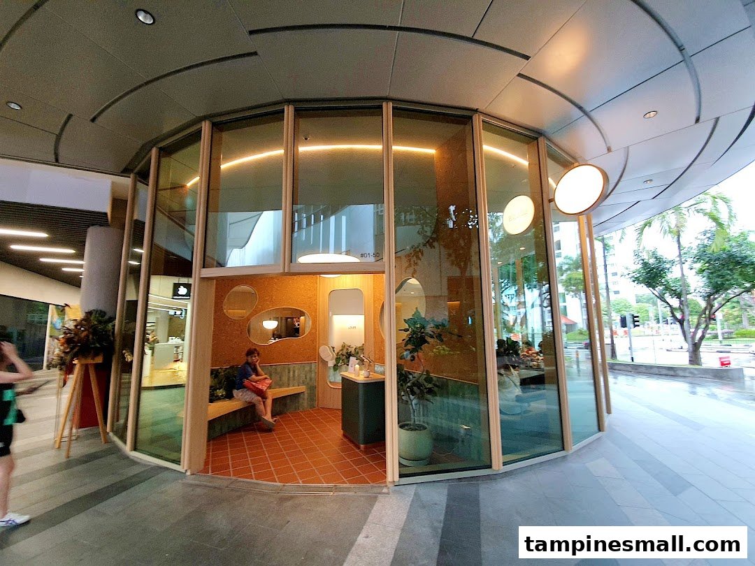 The modern, glass-fronted exterior of Lolas shop, featuring a cozy interior with seating and warm lighting.