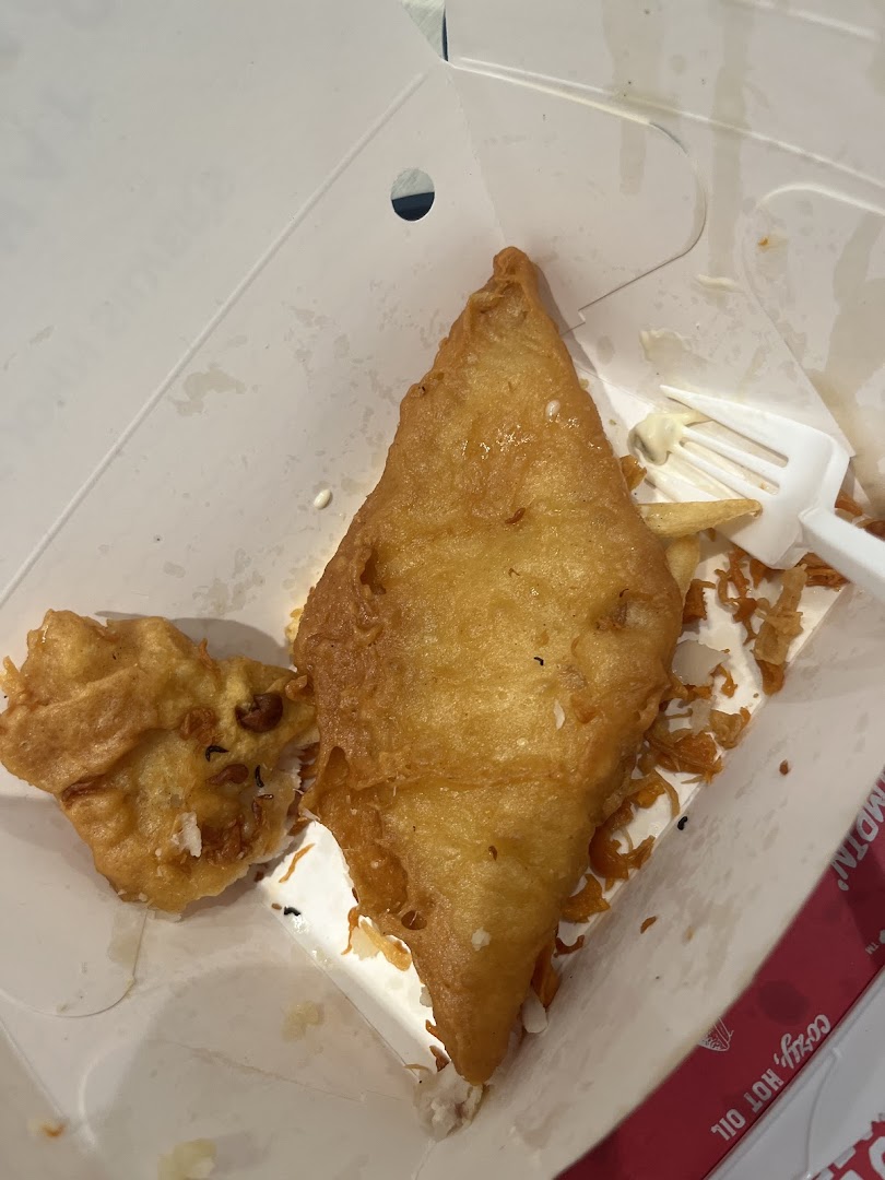 Close-up of golden-fried fish and a hushpuppy in a Long John Silver's take-out box.