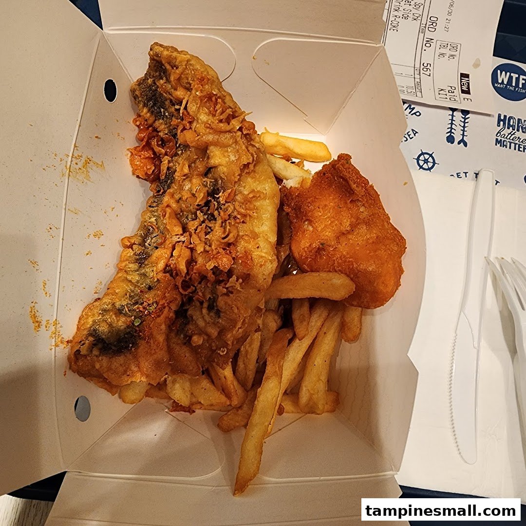 A close-up of crispy battered fish and golden fries in a takeaway box from Long John Silver's.