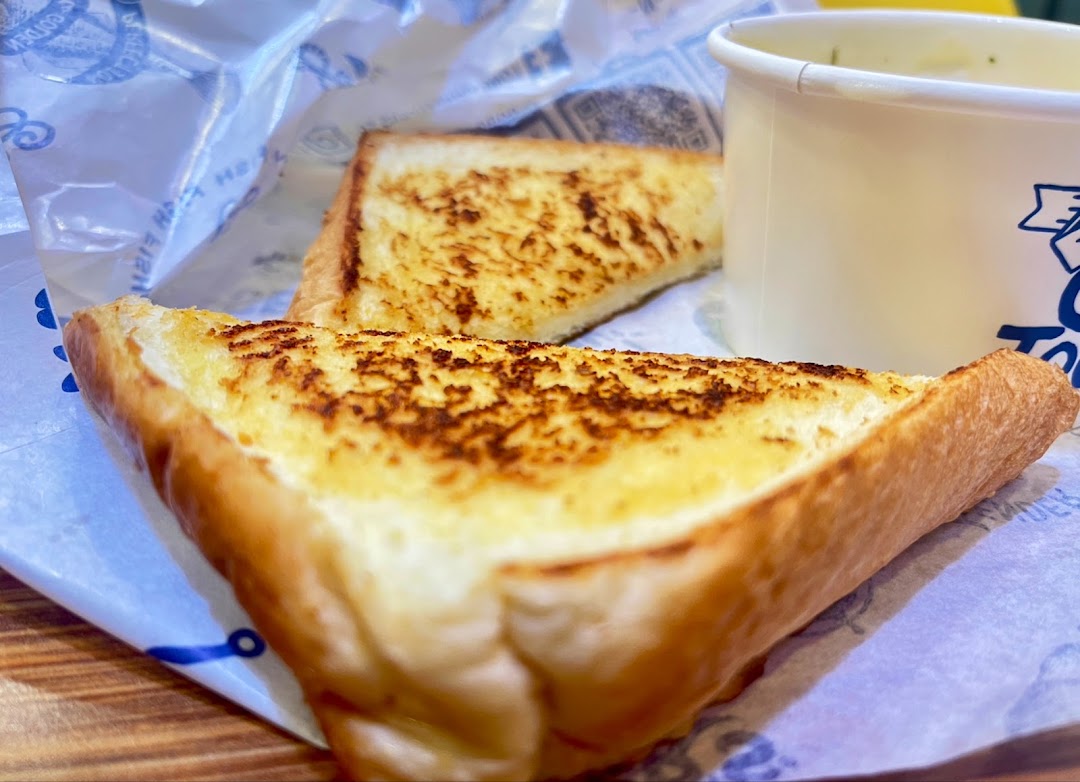 Two slices of golden-brown garlic bread and a cup of soup or chowder.