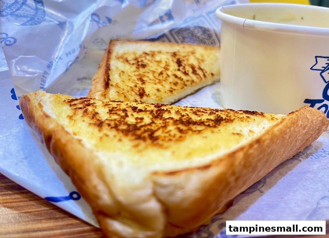Two slices of golden-brown garlic bread and a cup of soup or chowder.