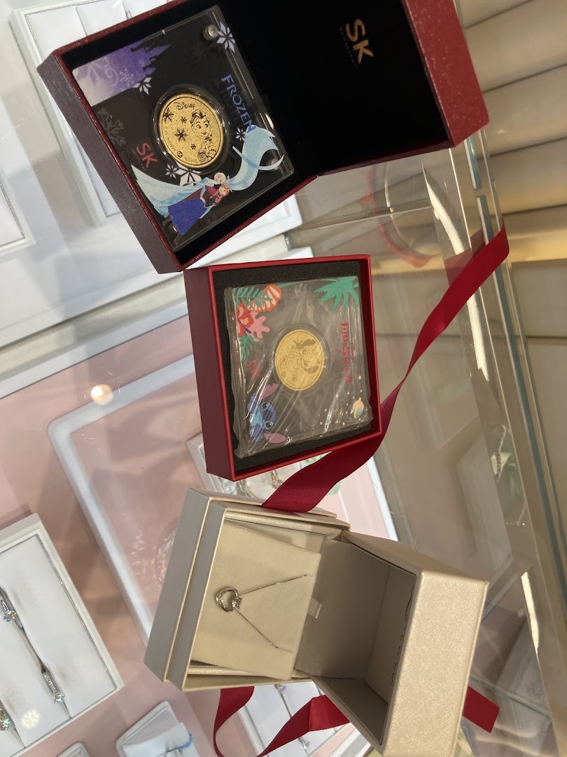 Close-up of a silver necklace and Disney-themed gold coins displayed in gift boxes.