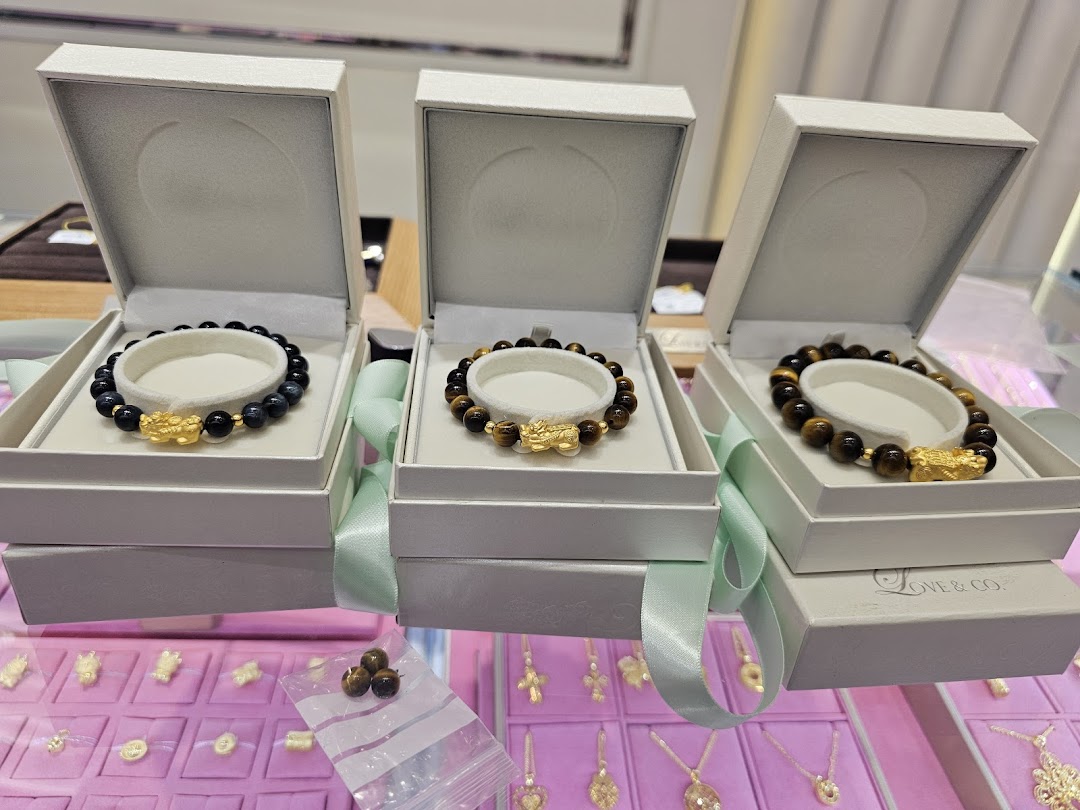 Three elegant beaded bracelets with gold charms displayed in white gift boxes at Love & Co.