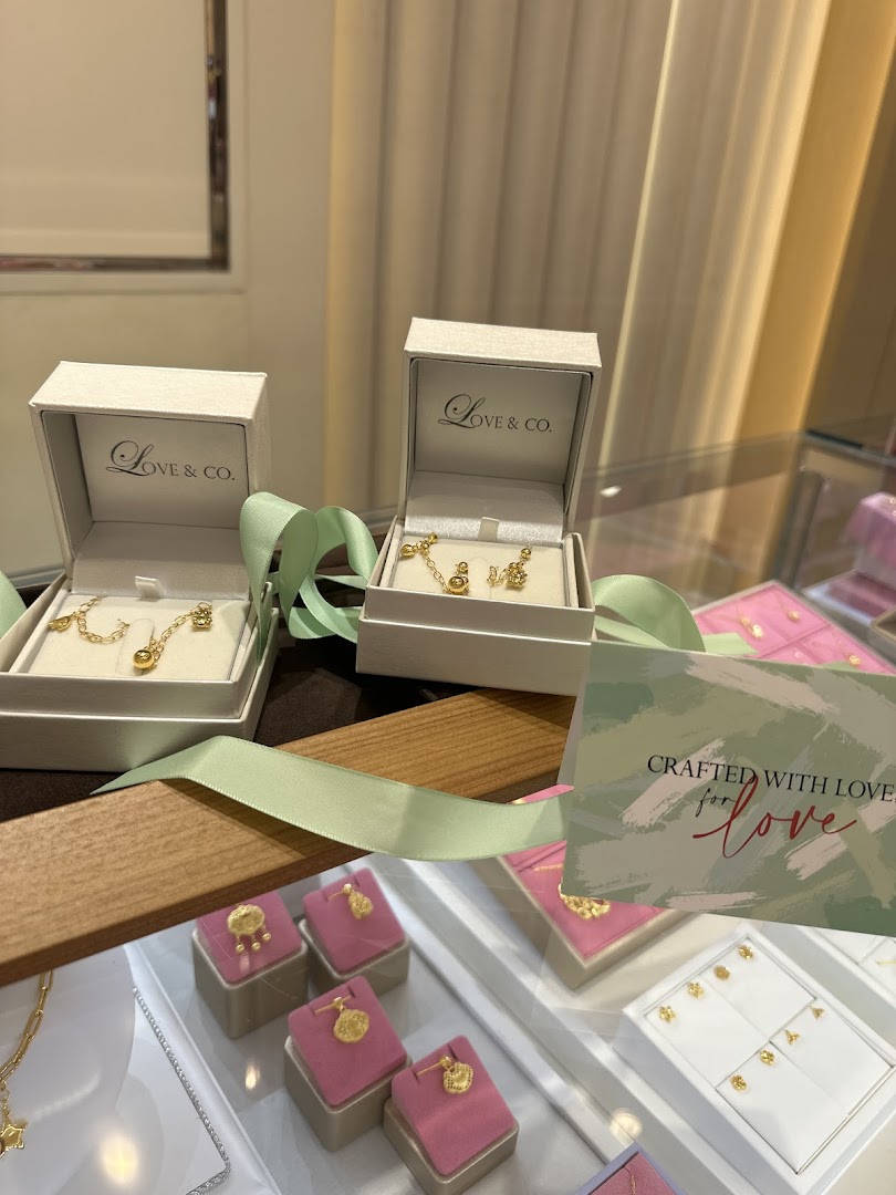 Close-up of exquisite gold jewelry, including necklaces and pendants, displayed in Love & Co. boxes and showcases.