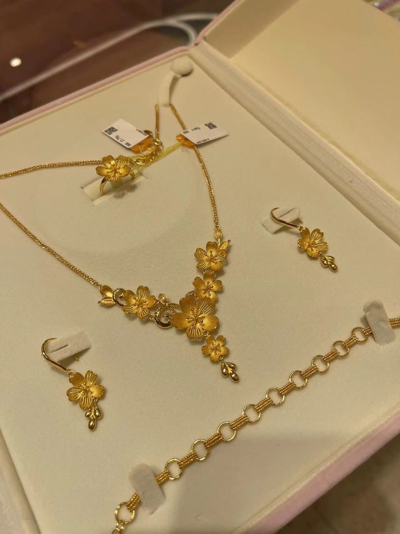 A beautiful gold jewelry set featuring intricate floral designs, including a necklace, ring, earrings, and bracelet.
