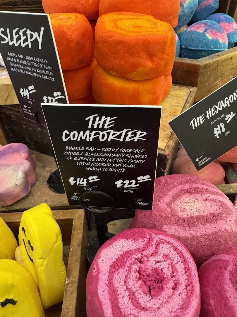 A vibrant display of Lush bubble bars and bath bombs, featuring 'Sleepy', 'The Comforter', and 'The Hexagon' products.