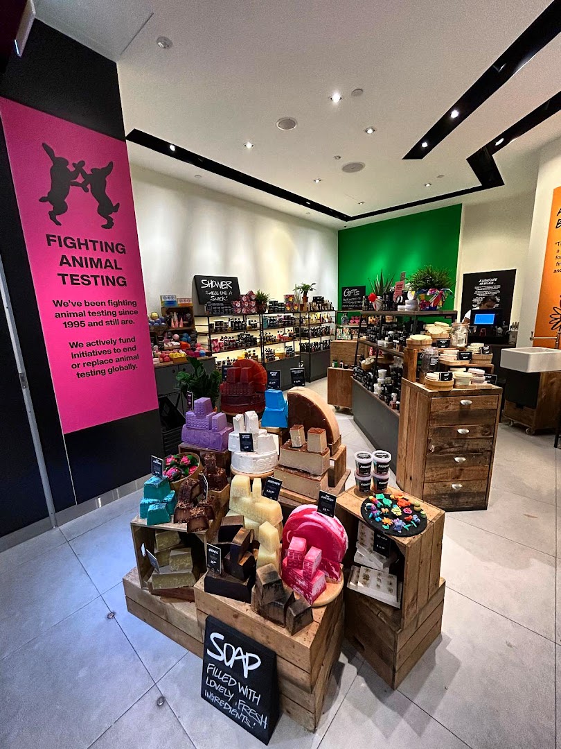 An interior view of Lush Fresh Handmade Cosmetics, showcasing colorful soaps and ethical messaging.