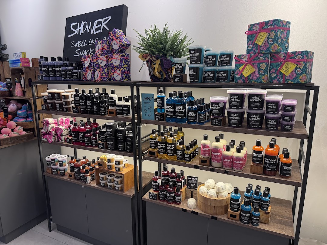 An interior shot of Lush Fresh Handmade Cosmetics, showcasing a vibrant display of bath and body products on wooden shelves.