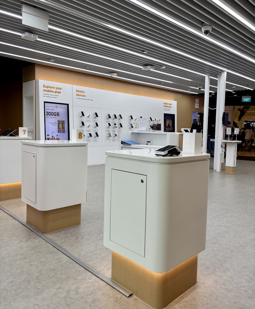 Interior of a modern M1 phone shop showcasing mobile devices and plan information displays.