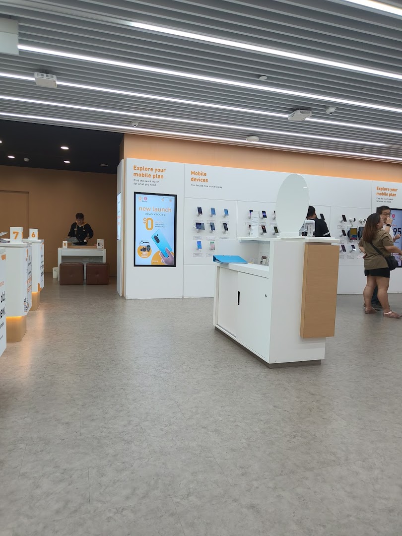 Interior view of a modern phone and internet service shop with mobile devices on display and customers browsing.