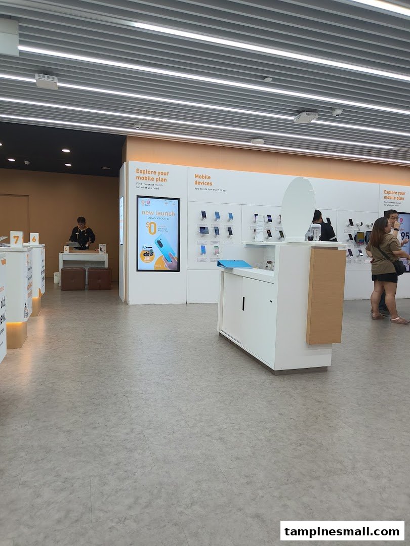 Interior view of a modern phone and internet service shop with mobile devices on display and customers browsing.