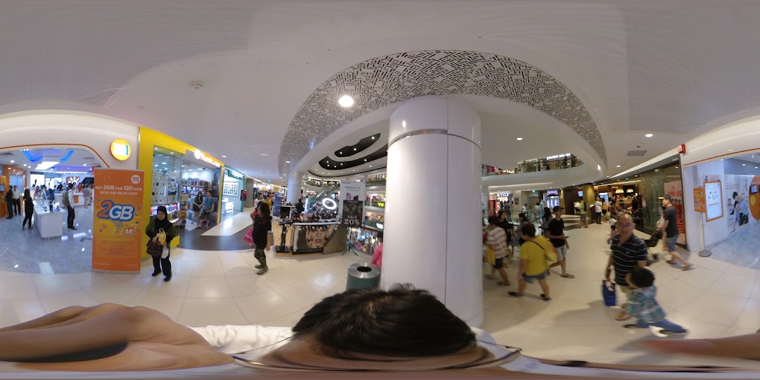 A wide-angle view of the M1 phone shop entrance in a bustling mall, featuring a promotional banner.