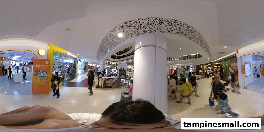 A wide-angle view of the M1 phone shop entrance in a bustling mall, featuring a promotional banner.
