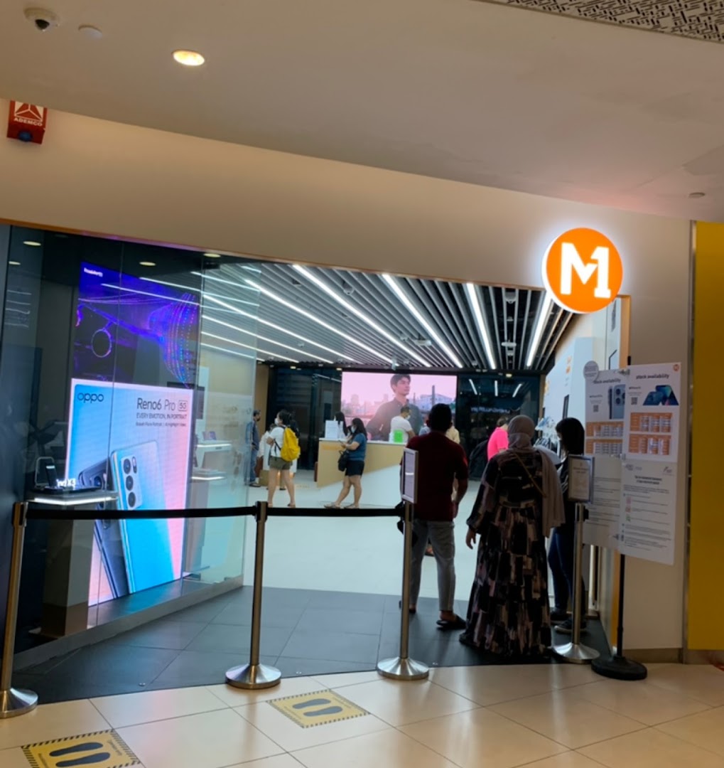 The M1 Tampines Mall shop entrance, showcasing phones and internet services, with customers inside.