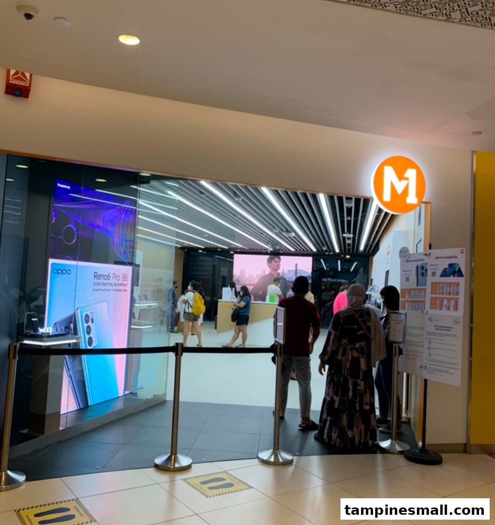 The M1 Tampines Mall shop entrance, showcasing phones and internet services, with customers inside.