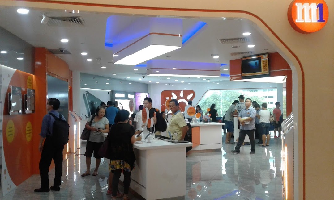 Customers browse phones and services inside a modern M1 telecommunications shop.