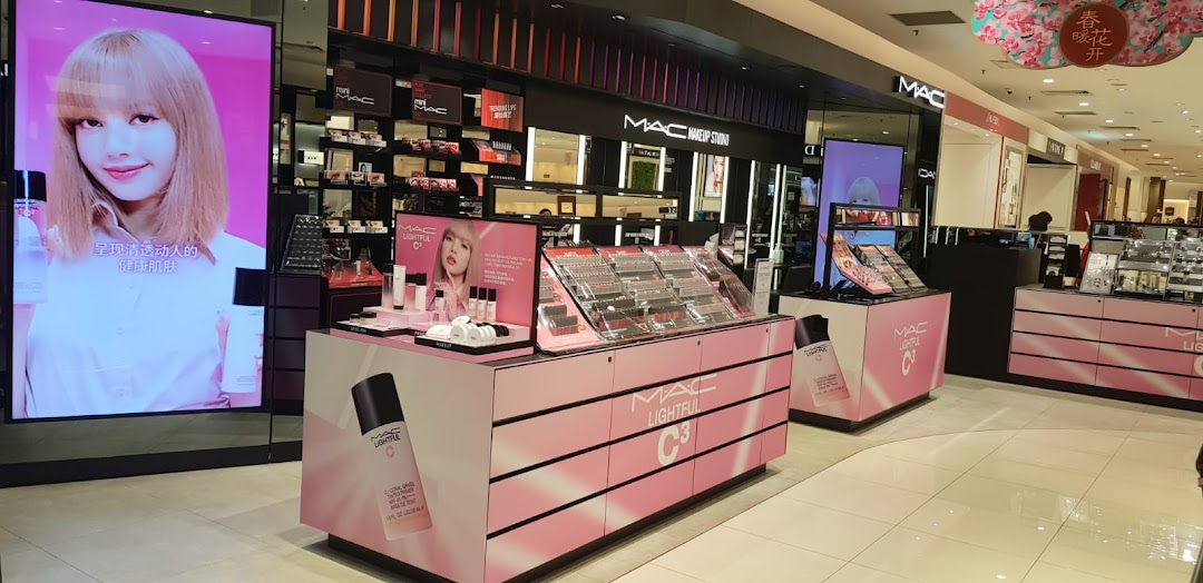 Interior view of MAC Cosmetics store with product displays, makeup studio, and a large digital screen.