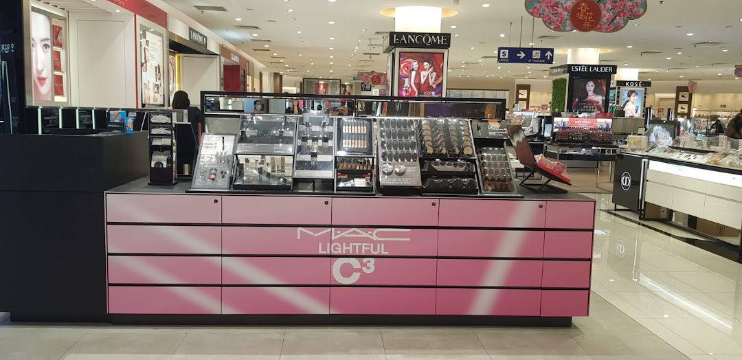 A MAC Cosmetics counter featuring makeup displays and products, located within a brightly lit department store.