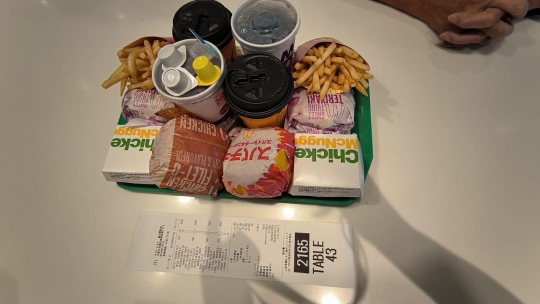 A tray of McDonald's food with burgers, fries, drinks, and McNuggets on a table, alongside a receipt.