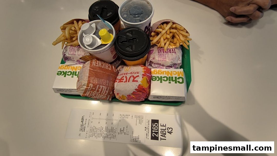 A tray of McDonald's food with burgers, fries, drinks, and McNuggets on a table, alongside a receipt.