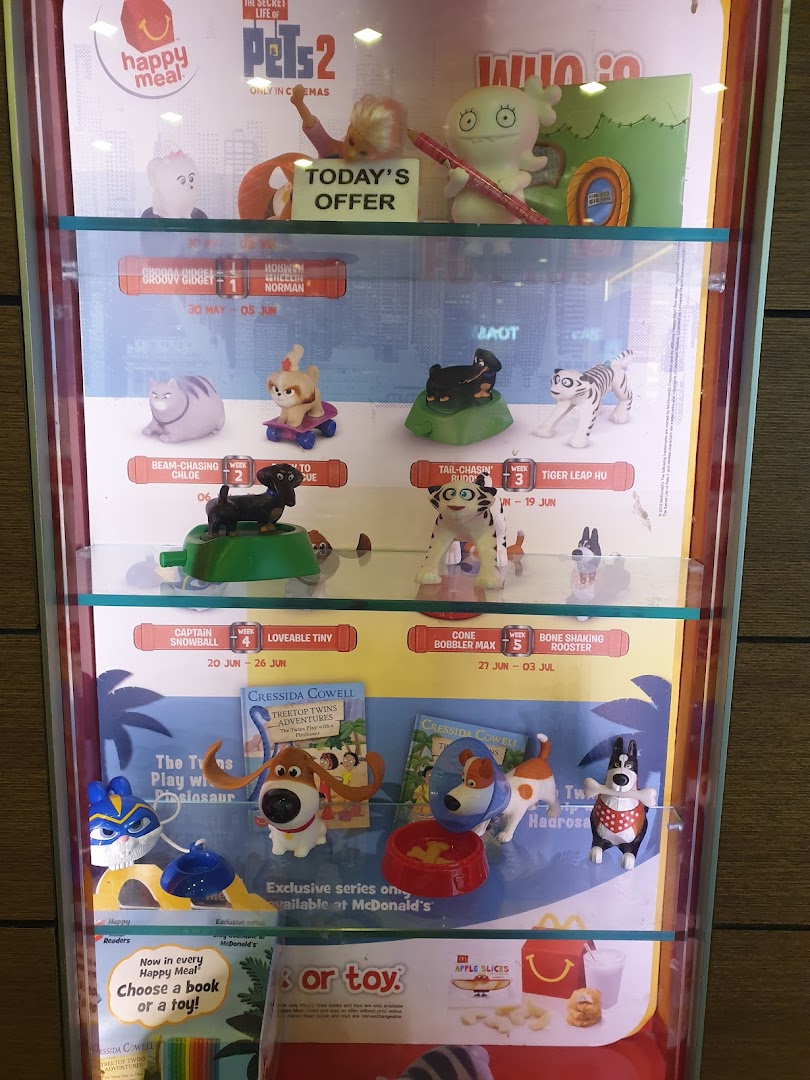 A display case showcasing McDonald's Happy Meal toys and book promotions, featuring 'The Secret Life of Pets 2' characters.