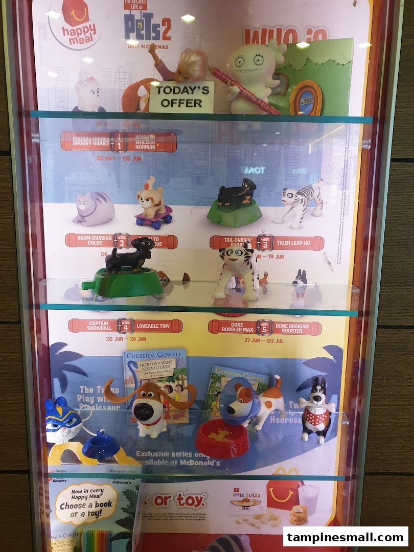 A display case showcasing McDonald's Happy Meal toys and book promotions, featuring 'The Secret Life of Pets 2' characters.