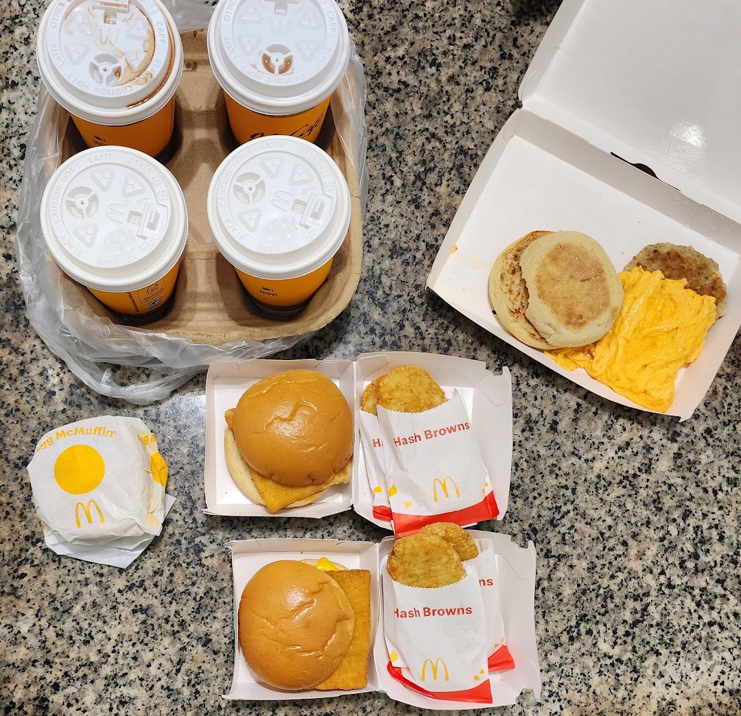 An overhead view of a McDonald's breakfast spread including drinks, hash browns, and various McMuffins.