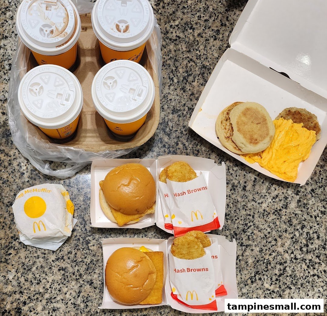 An overhead view of a McDonald's breakfast spread including drinks, hash browns, and various McMuffins.