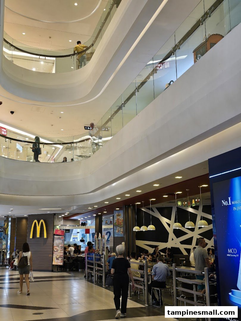 The bustling entrance and dining area of McDonald's Tampines Mall, seen from the mall's common area.